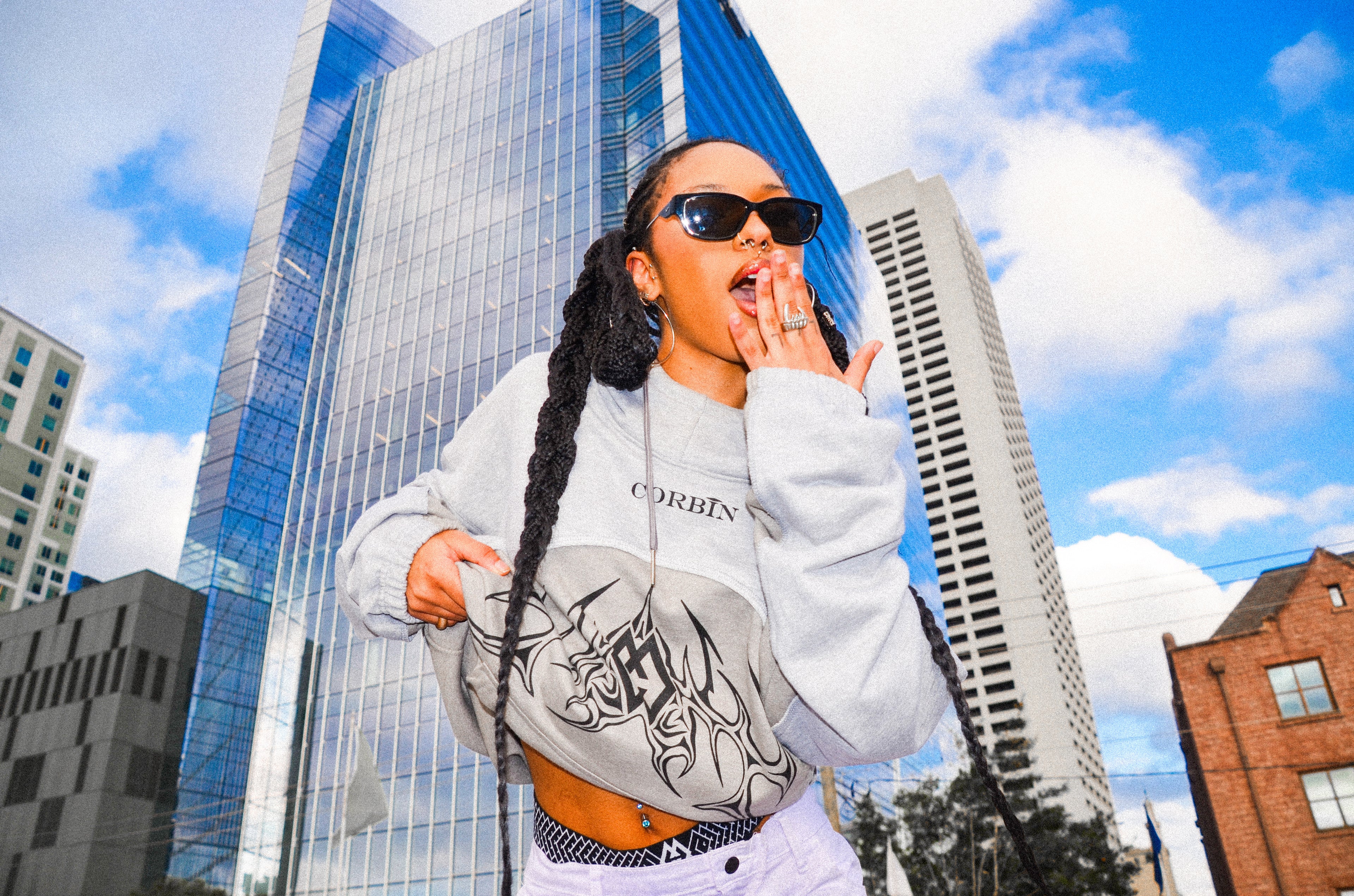 Stylish female model wearing a sleek gray Corbin hoodie, featuring a bold black logo centered on the chest for a modern, minimalist look.